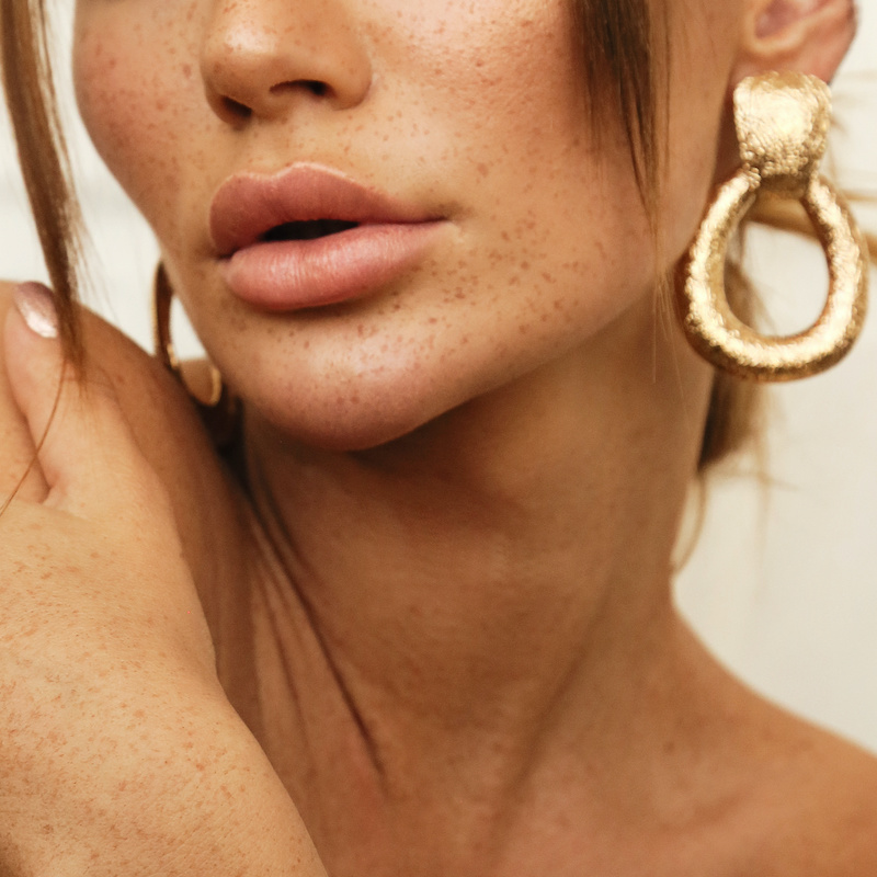 young woman with freckles wearing gold jewelry